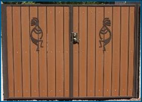 RV gate: Picture of custom iron gate with decorative figurines (kokopellis) and composite wood